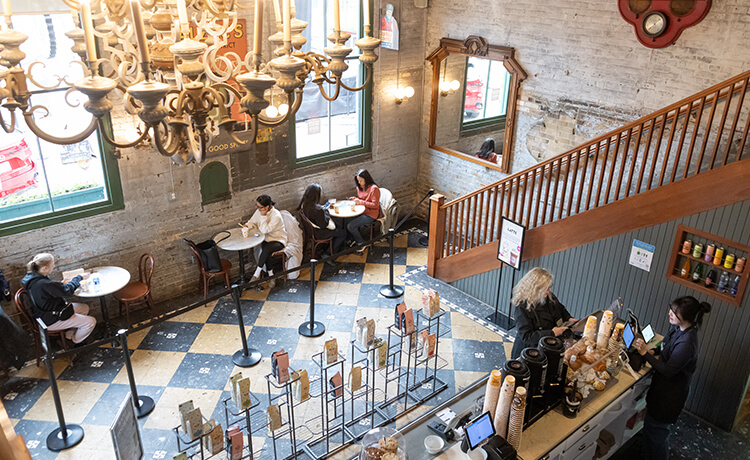 People sit at tables drinking coffee in an overhead view of Balzac’s Distillery District location.