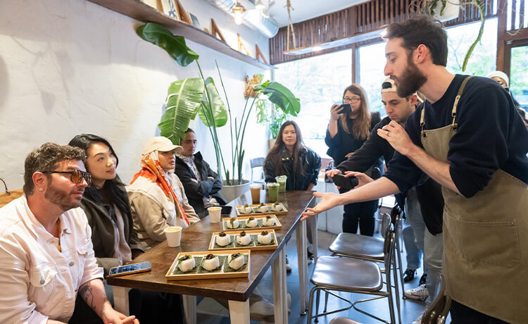 An employee presents a table of people with baked goods in Tsuchi Café.