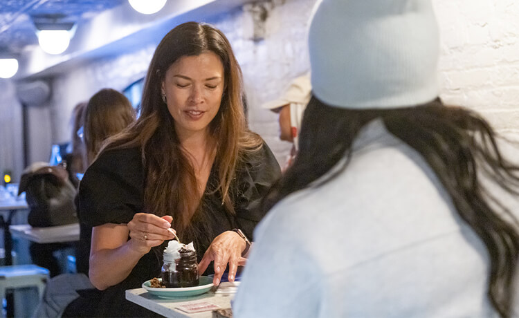 Two people sample a dessert while at a table at Piccolo Caffe E Vino. 