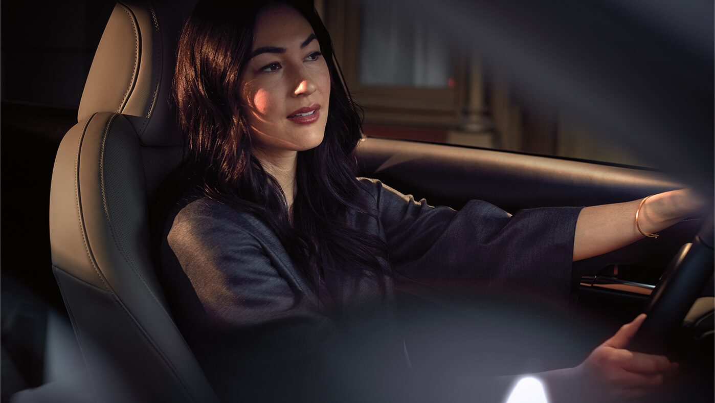 Pensive woman wearing blue blouse driving a Mazda