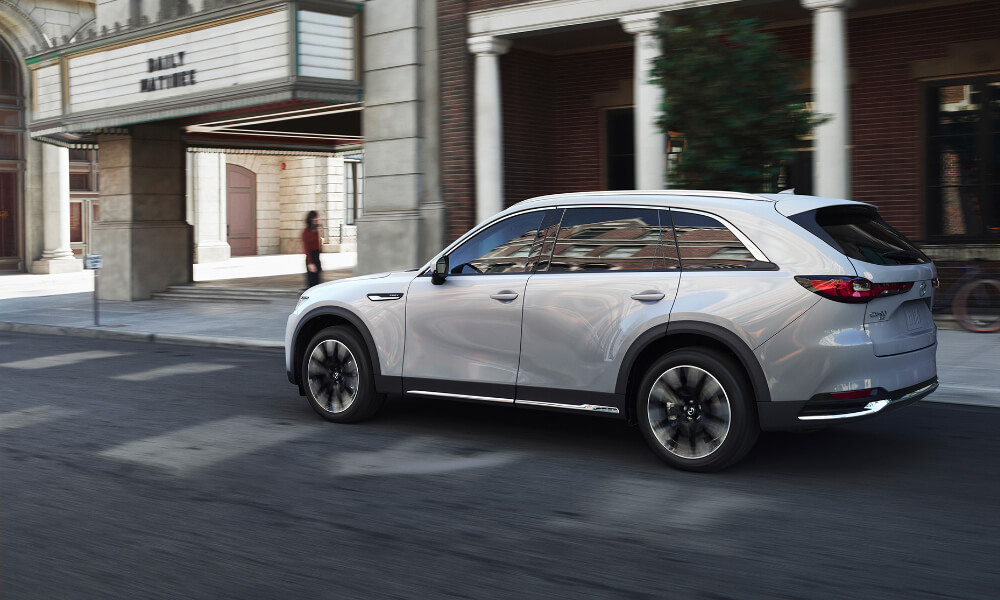 CX-90 PHEV drives past city theatre.