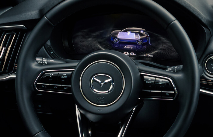 View of dash display behind the steering wheel inside the CX-90 PHEV shows battery level.  