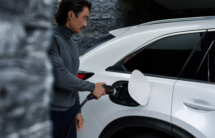 Driver plugging charger cord into CX-90 PHEV.  