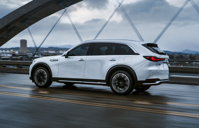 CX-90 PHEV driving across road on suspension bridge.