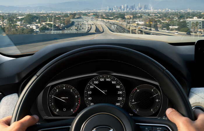 Point de vue d’un conducteur avec les mains sur le volant dans un véhicule en mouvement.