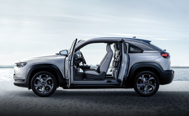 Side view of MX-30 with freestyle doors open at a beach. 