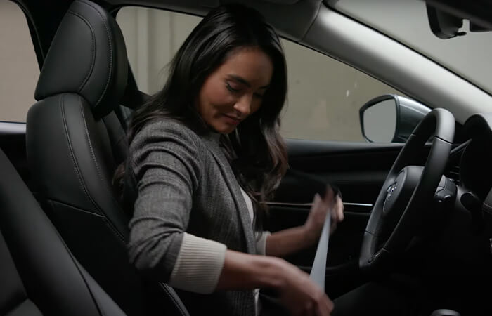 Driver confidently buckles seatbelt with a smile.  