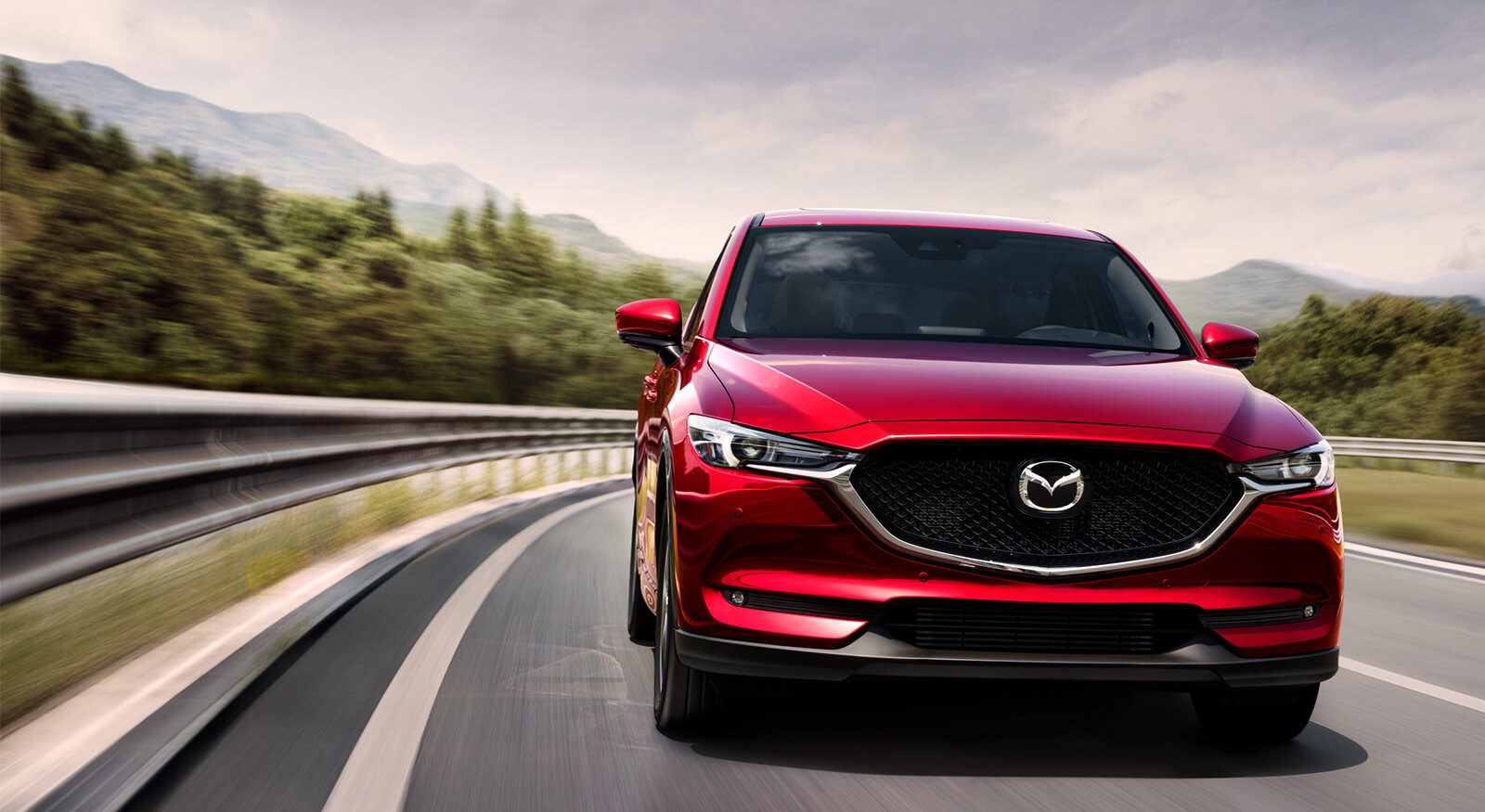Red Mazda SUV approaches on an open road