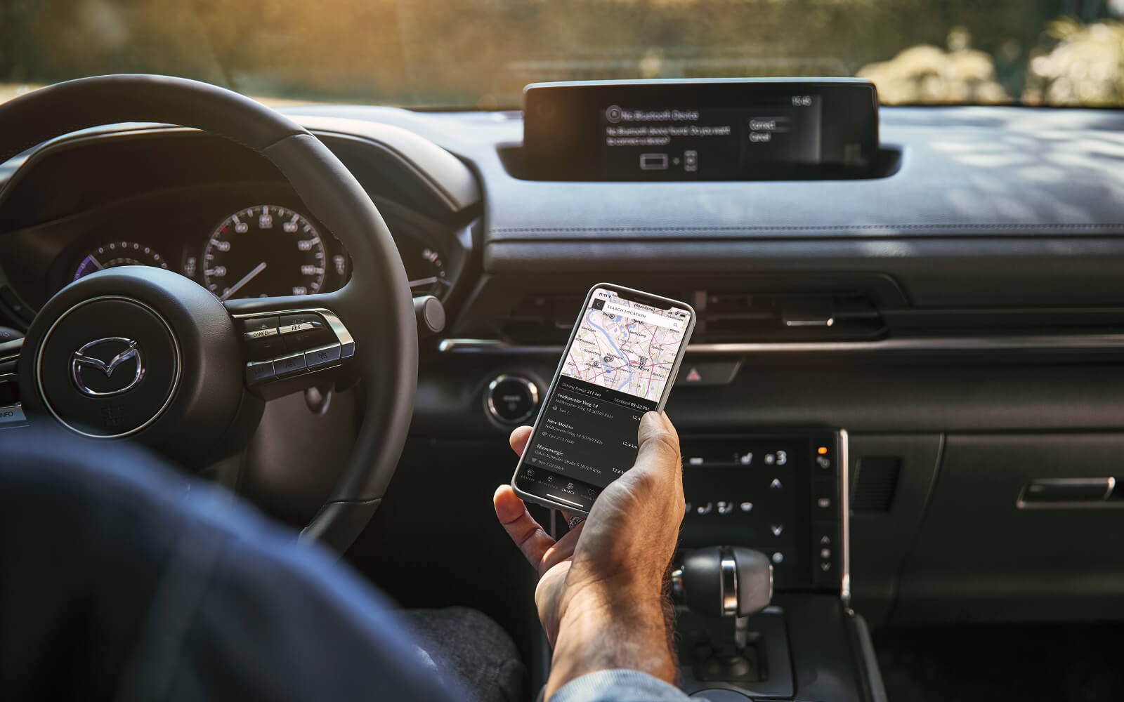 Driver’s right hand holds smartphone displaying map and driving directions 