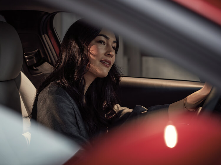 Woman driver smiles and tilts head slightly while driving 