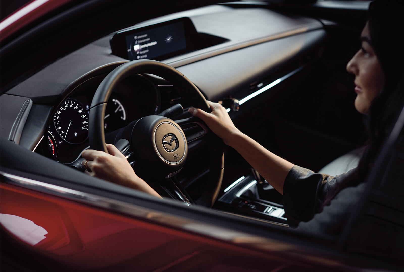 Woman holding steering wheel in both hands.