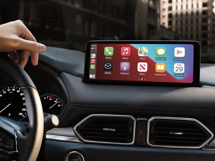 Hand on steering wheel with Mazda Connect screen visible on dashboard