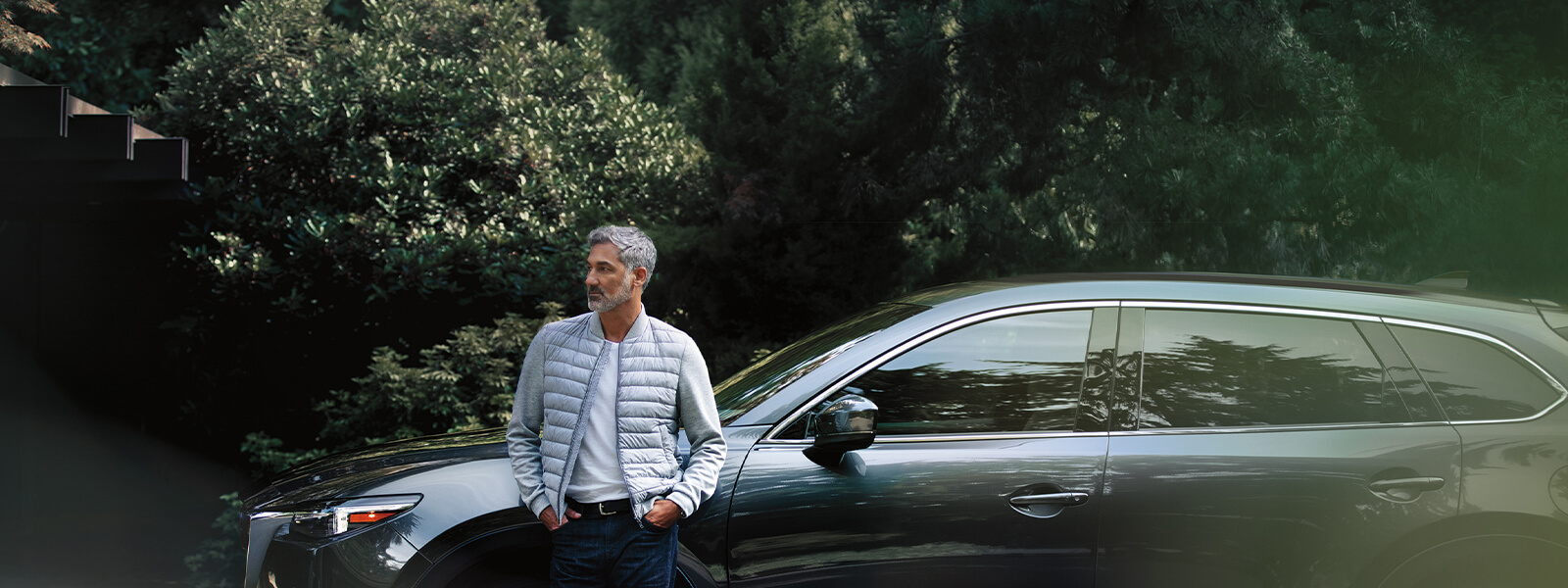 Man in grey suit exiting retailer showroom looks over shoulder at Deep Crystal Blue Mica Mazda3 Sport on display