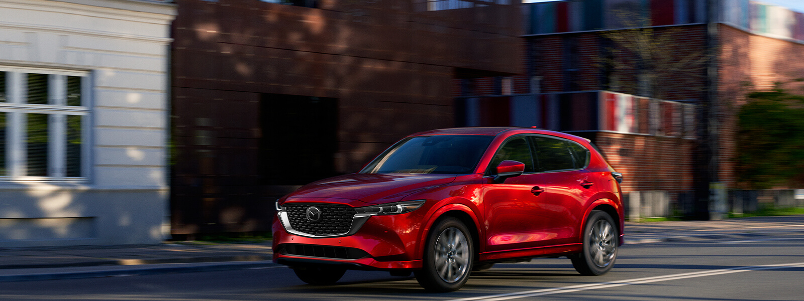 Red Mazda SUV turning corner on cobblestone street