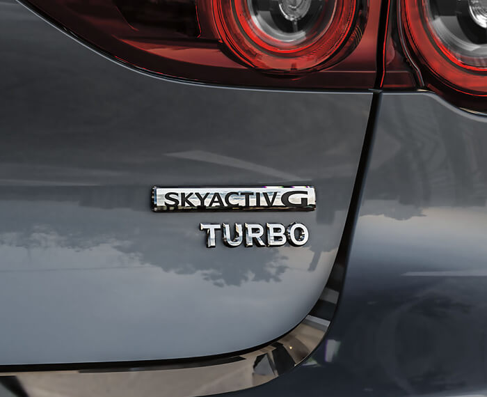 Close-up of Skyactiv-G TURBO badge and Mazda logo on rear hatch door.