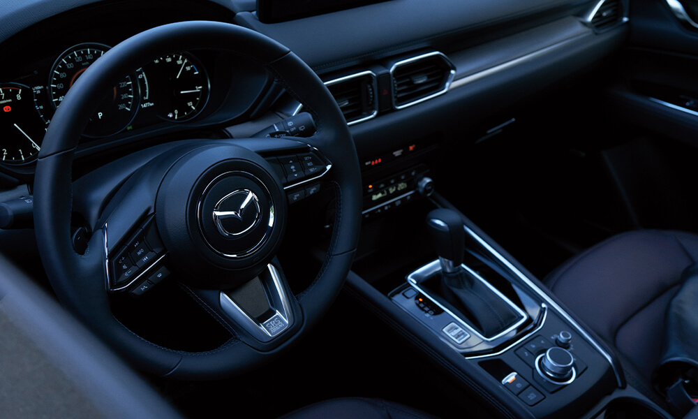Top-down view of Mazda CX-5 driver’s side showing steering wheel, gear shifter, and control console.