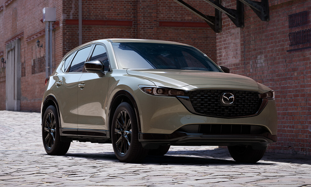 Suna Edition Mazda front side profile parked next to brick wall.