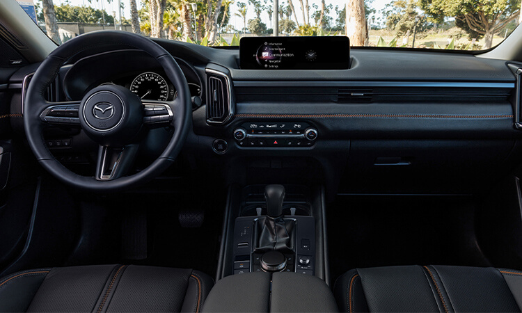 Interior centre view looking forward showing seats, cockpit, dash and console in black leather with red stitching.
