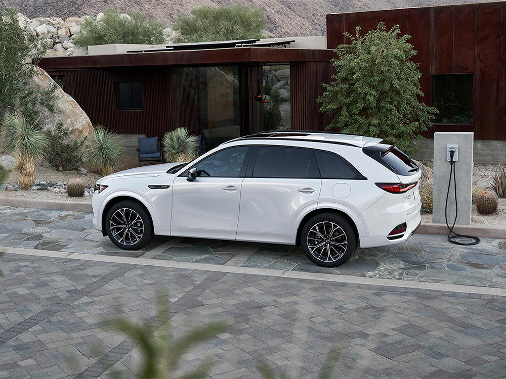 White CX-70 PHEV parked at a charging station.