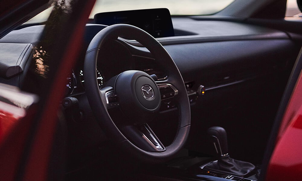 Close-up view of the Mazda CX-30 steering wheel from the open driver-side door.