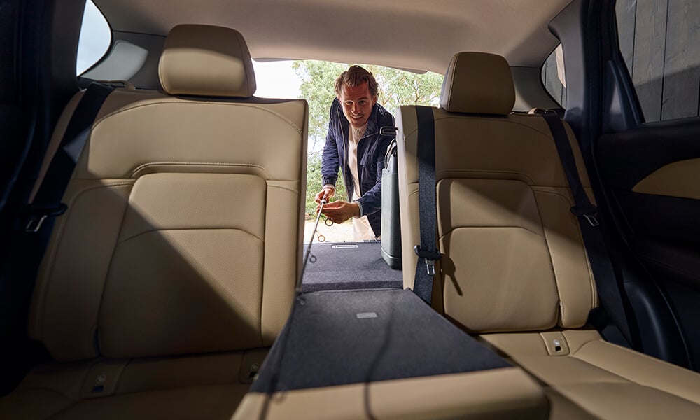View from the back seats of a Mazda CX-5, showing a man folding down the middle rear seat.