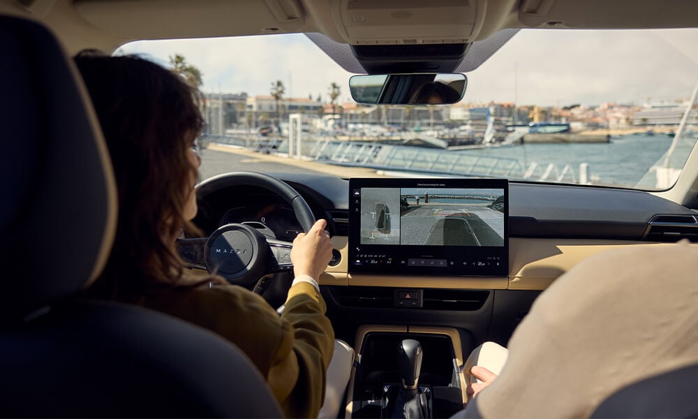 A woman opening the driver side door of a Soul Red Crystal Metallic Mazda CX-30