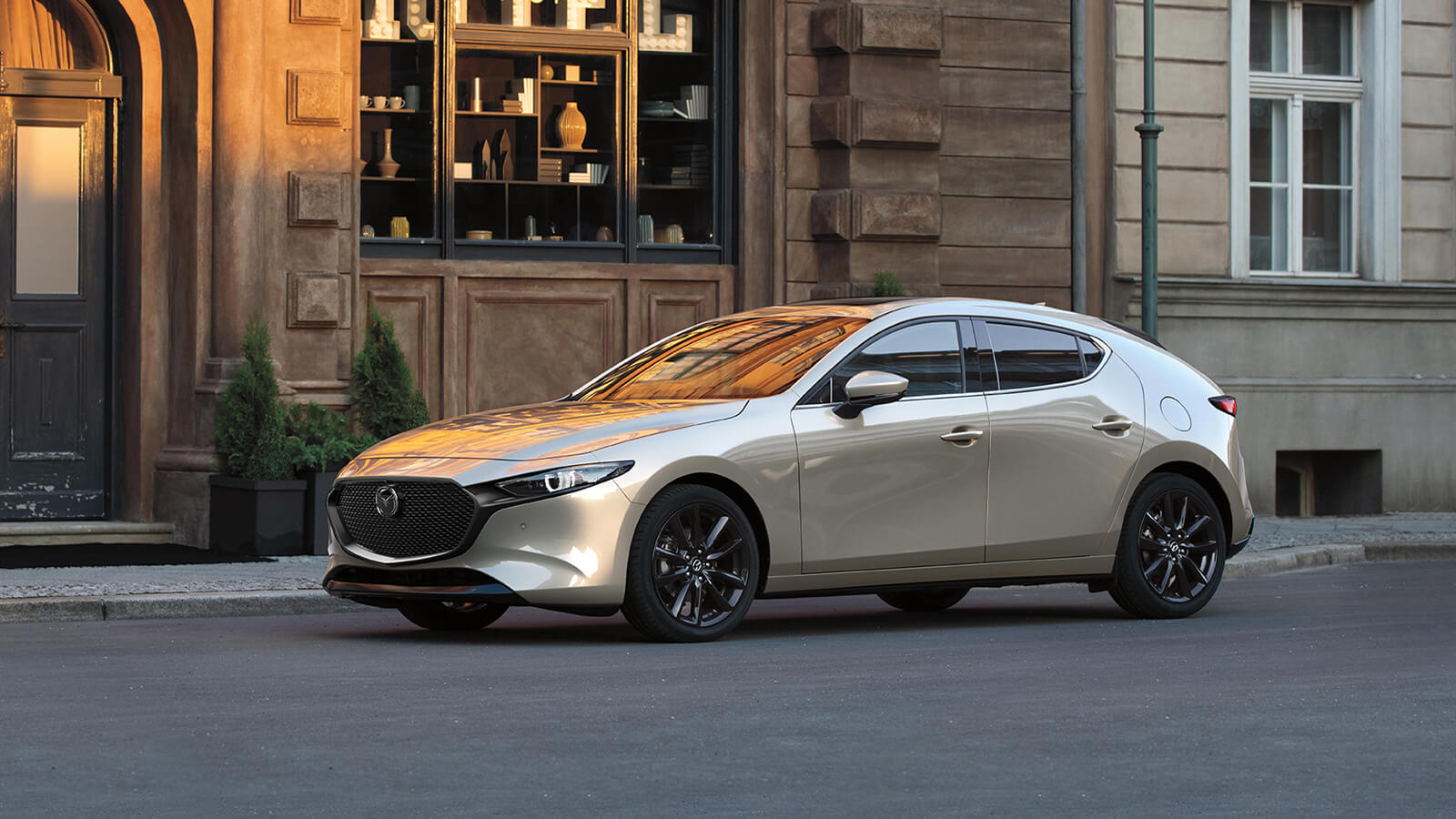 Side profile of a Platinum Quartz Metallic Mazda3 Sport parked on a quiet street.