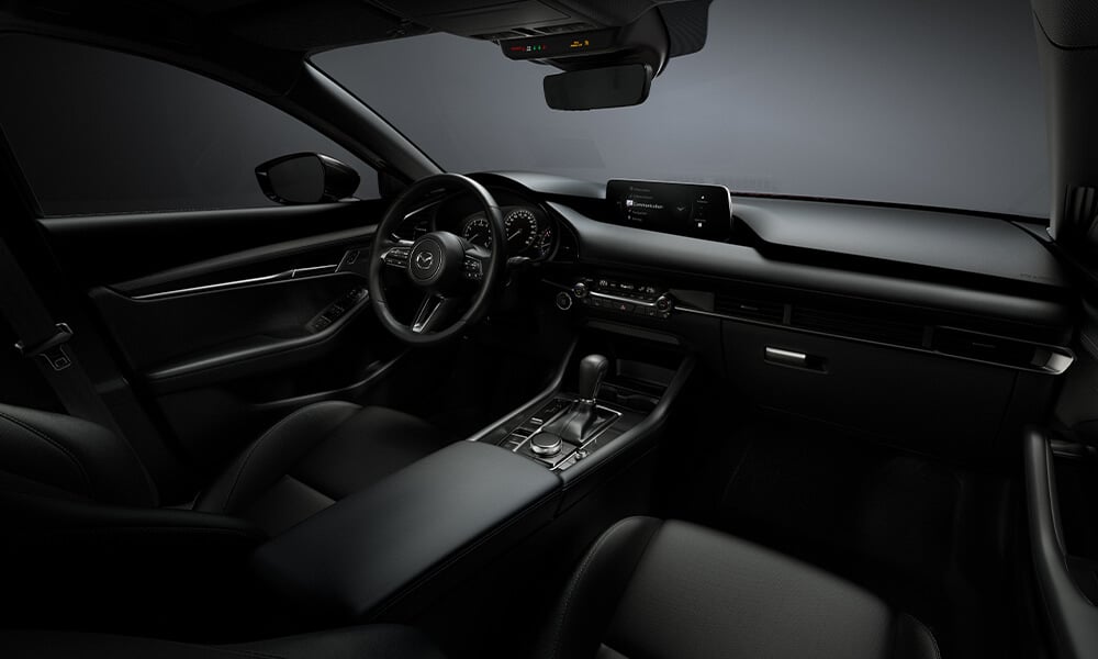 Passenger-side view of a Mazda3 Sport interior, showing the driver’s control and steering wheel.